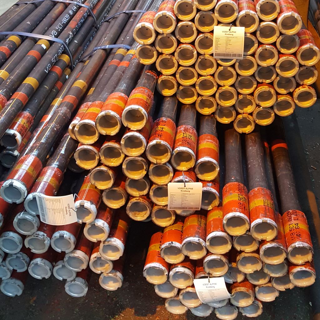 Stacks of metal pipes bundled together, arranged in rows inside an industrial warehouse.